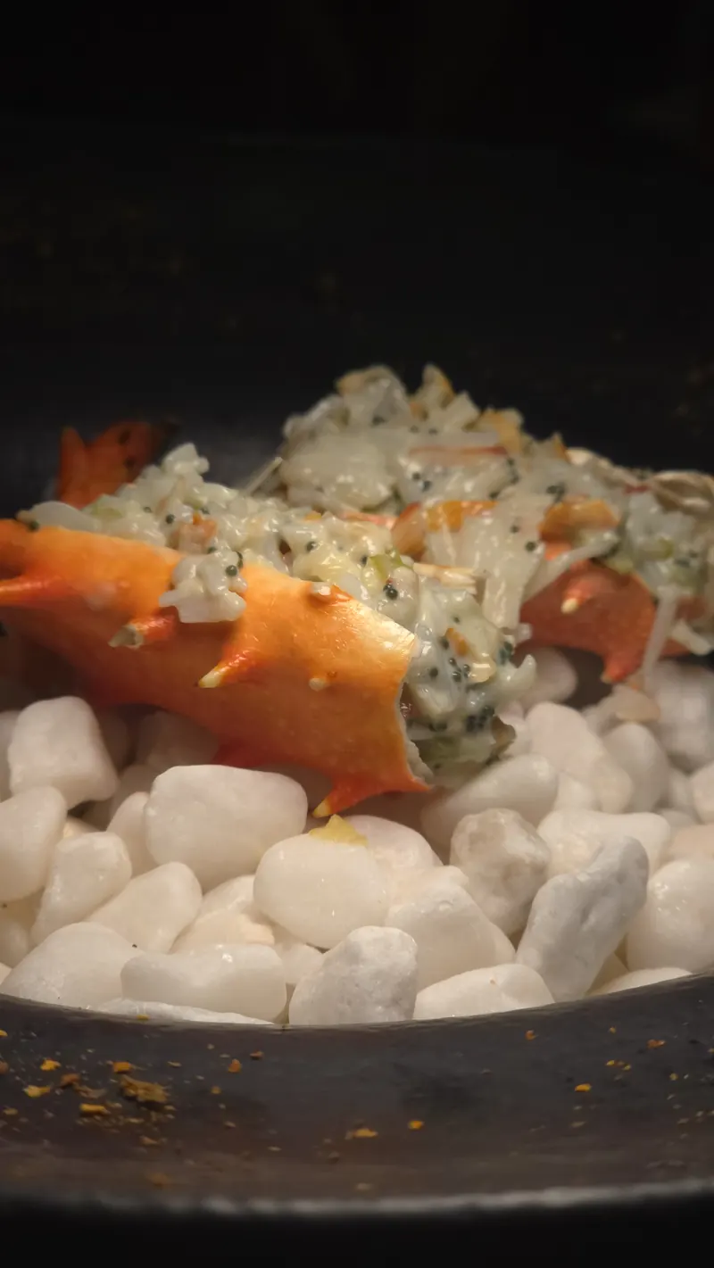 Pata de king crab gratinada servida sobre pedras